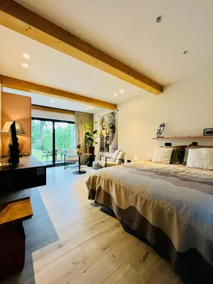 a bedroom with a large bed and a living room at Via Caput in Lokeren
