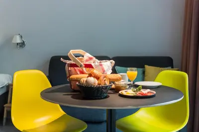 a table with a basket of food on it with yellow chairs at Marcel de Gand Business & Travel in Ghent