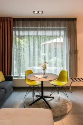 a living room with a table and yellow chairs at Marcel de Gand Business & Travel in Ghent
