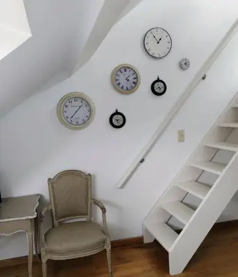 a room with clocks on the wall and a chair at L Heure Bleue in Wezembeek-Oppem