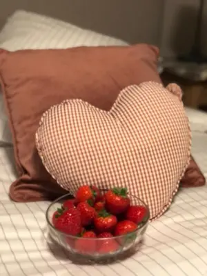 a heart pillow and a bowl of strawberries on a bed at NeNe in Dilbeek