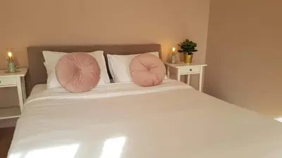 a white bed with two pink pillows on it at BnB Antwerpen - CHIQUE in Antwerp