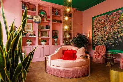a living room with pink walls and a chair with a red pillow at Flora in Antwerp