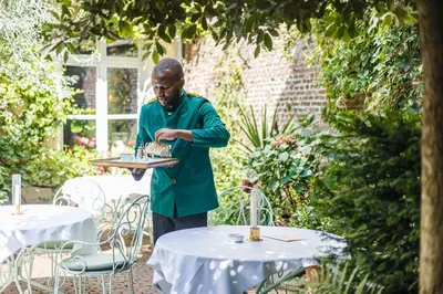 a man holding a plate with a cake on a table at Flora in Antwerp