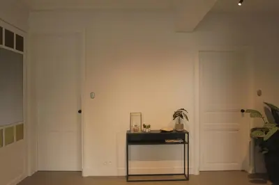 a room with a white wall and a table with a mirror at MAISON KITOKO in Ghent