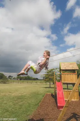 a little girl jumping off of a playground at Lavendelhof luxe wellnesshouse in Zottegem