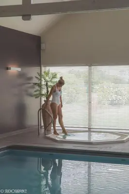 a woman is standing next to a swimming pool at Lavendelhof luxe wellnesshouse in Zottegem