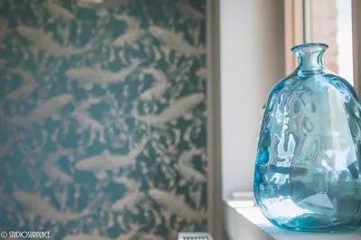 a blue glass vase sitting on a shelf next to a wall at Lavendelhof luxe wellnesshouse in Zottegem