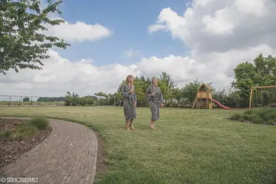 two women standing in a field with a playground at Lavendelhof luxe wellnesshouse in Zottegem