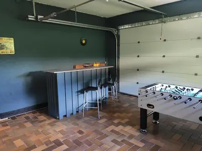 a bar with stools and a table in a room at Villa Chill in Scherpenheuvel-Zichem