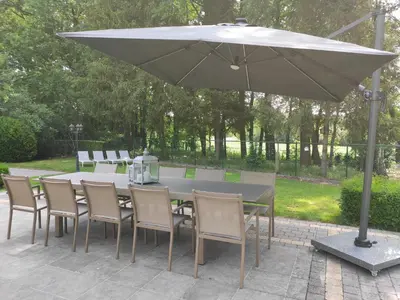 a table with chairs and an umbrella on a patio at Villa Chill in Scherpenheuvel-Zichem