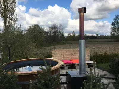 a hot tub in a garden with a woodburning stove at Landgoed Omorika in Ravels