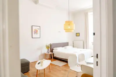 a white bedroom with a bed and a table and chairs at Smart Appart - Gare Du Midi in Brussels