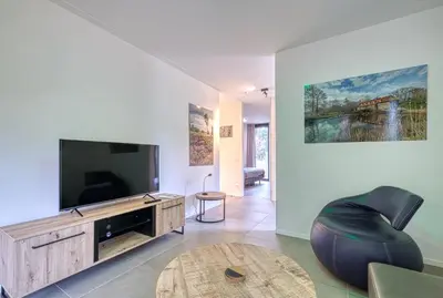 a living room with a flat screen tv and a black chair at Black Box in Lille