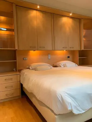 a bedroom with a large white bed and wooden cabinets at lovely two bedroom apartment with free parking in Antwerp