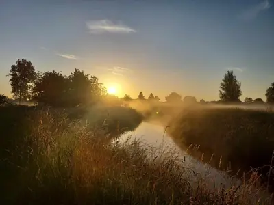 a misty sunrise over a river in a field at Rustig gelegen chalet Kapeki met tuin aan het water in Geel