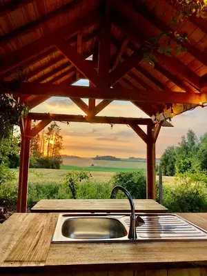 a kitchen with a sink under a wooden pergola at Cowcooning / Family tents in Huldenberg