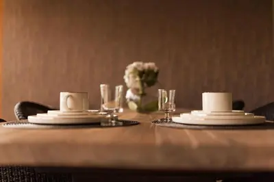 a table with two white dishes and a vase with flowers at B&B Maison Lize in Lievegem