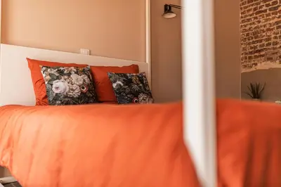 a bedroom with a bed with orange sheets and pillows at B&B Maison Lize in Lievegem