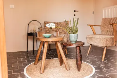 a living room with two tables and a chair at B&B Maison Lize in Lievegem