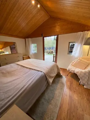 a bedroom with a large bed and a large window at Le Petit Chalet avec hottub. in Sint-Gillis-Waas