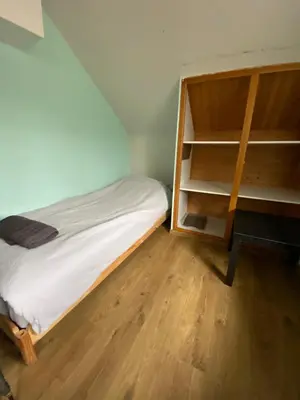 a small bedroom with a bed and a book shelf at Le Petit Chalet avec hottub. in Sint-Gillis-Waas