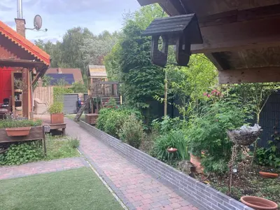 a garden with a patio with a bench and plants at Le Petit Chalet avec hottub. in Sint-Gillis-Waas