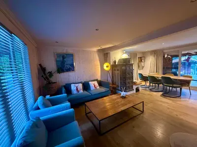 a living room with a blue couch and a table at Le Petit Chalet avec hottub. in Sint-Gillis-Waas