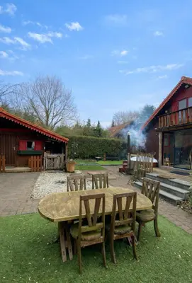 a wooden table and chairs in front of a building at Le Petit Chalet avec hottub. in Sint-Gillis-Waas