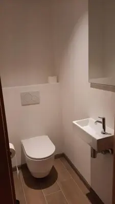 a white bathroom with a toilet and a sink at The Kettle House - Stable in Sint-Pieters-Leeuw