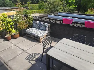 a patio with a bench and tables on a roof at Gasthuis Puytvoet in Sint-Niklaas