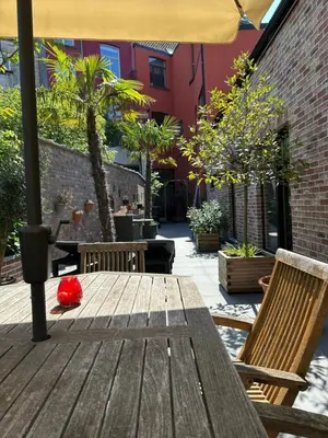 a wooden table with chairs and an umbrella on a patio at Freetimeflat Mies & Fien in Ghent
