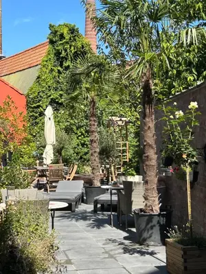 a patio with tables and chairs and a palm tree at Freetimeflat Mies & Fien in Ghent
