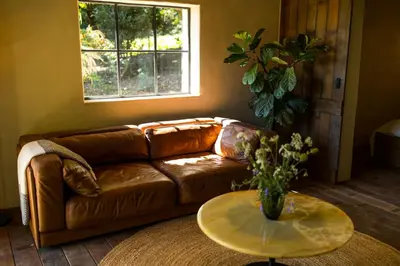 a brown leather couch in a living room with a table at The cabin Morris in Holsbeek