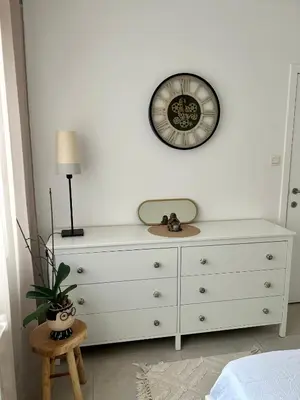 a white dresser with a clock on a wall at Vintage dream in Heide