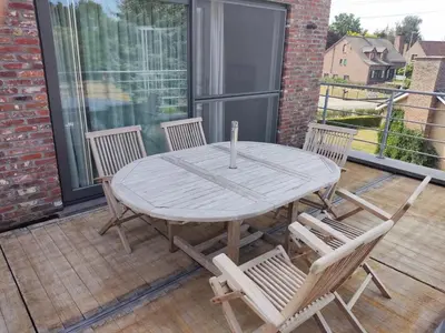 a wooden table and chairs on a patio with a window at Vakantiewoning Op Den Briel in Lokeren