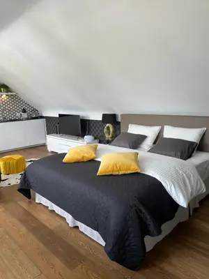 a bedroom with a large bed with yellow pillows at Rooftop terrace suite in Heist-op-den-Berg