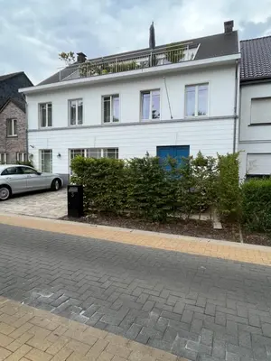 a white house with a car parked in front of it at Rooftop terrace suite in Heist-op-den-Berg