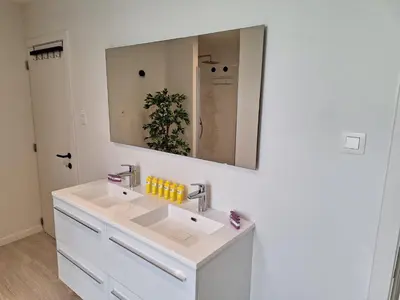 a white bathroom with a sink and a mirror at Huis ALNA 2 in Mechelen