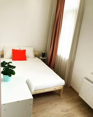 a small bedroom with a bed with a red pillow at Benny's Rooms Brussels City Centre in Brussels