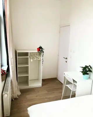 a small white room with a table and a desk at Benny's Rooms Brussels City Centre in Brussels