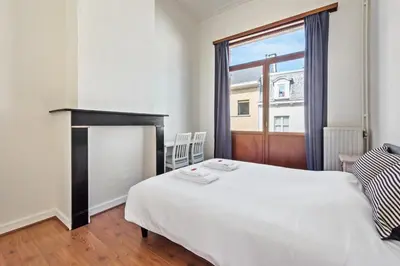a bedroom with a white bed and a fireplace at The Old One Fifteen by Romy&Travis in Ghent