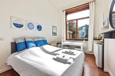 a bedroom with a white bed with blue pillows and a window at The Old One Fifteen by Romy&Travis in Ghent