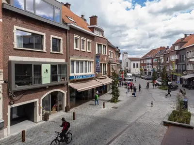 a man riding a bike down a street with buildings at Georges & Madeleine Apartments in Aalst