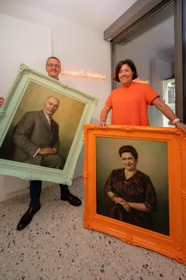 a woman standing next to two framed portraits of a man at Georges & Madeleine Apartments in Aalst
