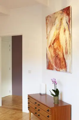 a painting hanging on a wall above a wooden dresser at B2B-flats in Ternat