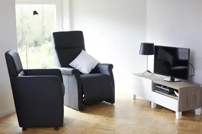 a living room with a black chair and a television at B2B-flats in Ternat