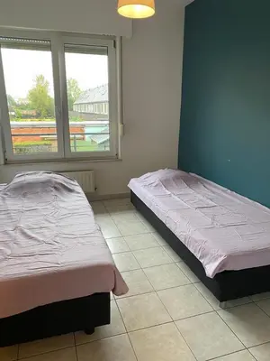 two beds in a room with two windows at Superbe appartement lumineux et spacieux in Antwerp