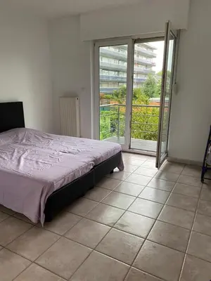 a bedroom with a bed and a large window at Superbe appartement lumineux et spacieux in Antwerp