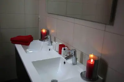 a bathroom with two red candles on a sink at B&B Hippo-Droom in Hoeilaart